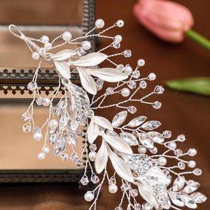 Silver bridal headband with alloy leaves, rhinestones and pearls on a vintage glass box