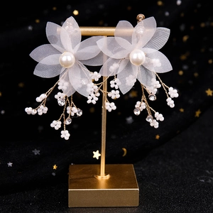 Détail de boucles d'oreilles fleurs en tulle blanc avec glands perlés sur support doré