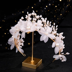 Détail du serre-tête de mariée avec fleurs en tissu et perles sur support doré