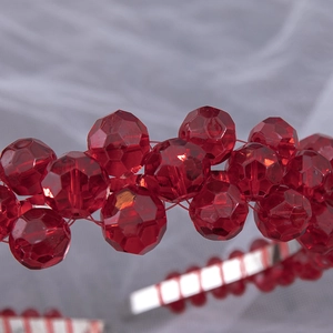 Vue détaillée des perles de cristal rouge à facettes et du cadre argenté du serre-tête