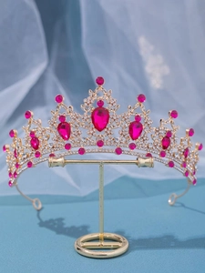 Detail of golden baroque crown with rose red crystals and diamonds on organza background