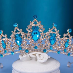 Close-up of royal crown with blue pear-shaped rhinestones on a gold-plated alloy frame