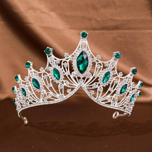 Macro shot of silver alloy baroque crown with marquise emerald stones and diamonds