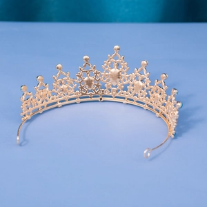 Detailed close-up of golden baroque tiara with heart patterns and blue rhinestones
