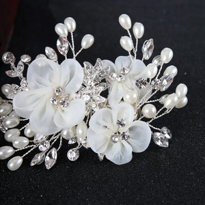 Exquisite bridal hair clip with white gauze flowers, pearls, and crystals on a dark background