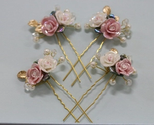 Detail view of 4-piece bridal hair pins with pink ceramic roses and golden leaf accents