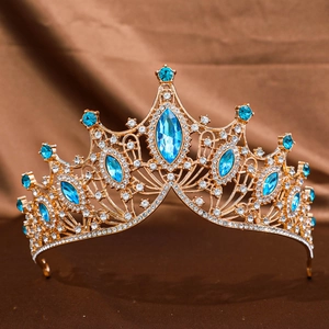 Close-up of golden Baroque crown with horse-eye blue rhinestones on silk background