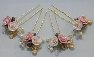 Detail of four handmade gold bridal hair pins with pink roses and white pearls