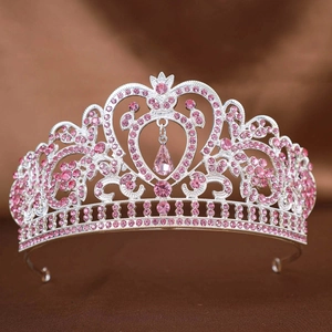 Macro detail of silver baroque crown featuring pink rhinestones and a heart shaped pendant