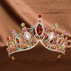 Vintage baroque gold tiara with colorful rhinestones and a red center gem on silk fabric