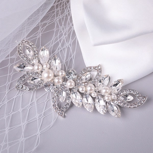 Gros plan d'un peigne à cheveux pour mariée avec strass et perles sur du satin blanc