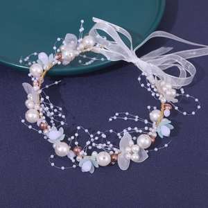 Detailed macro view of handmade bridal hairband with pearls, gold leaves and organza ribbon