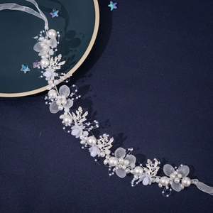 Handmade bridal headband with pearls, fabric flowers and silver leaves on blue background