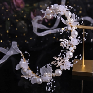 Elegant bridal headband with white pearls, frosted flowers, and gold leaves on dark backdrop
