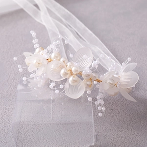 Detailed shot of bridal headband with pearls, frosted petals, and gold wire ribbon