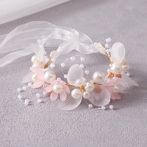 Macro shot of handmade bridal headband with pink flowers, pearls and golden leaves