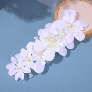 Detailed view of handmade bridal hairpiece with white fabric flowers and pearl accents