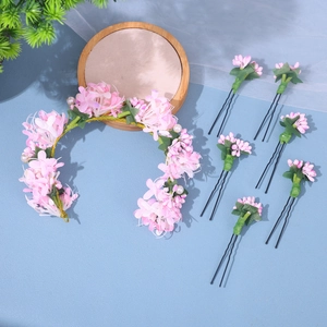 Detailed set of pink floral bridal hairpins and wreath with pearls on a blue surface
