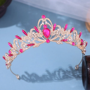 Dettaglio ravvicinato della corona da sposa dorata con gemme rosa a goccia e cristalli bianchi