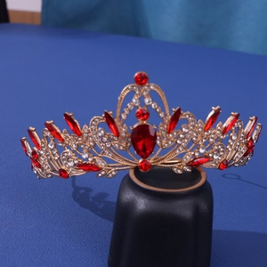 Luxurious gold crown with red teardrop rhinestones on dark blue background