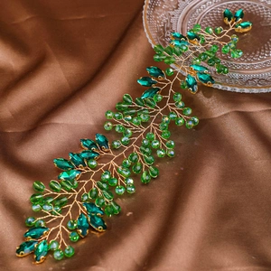 Detail of handmade gold wire hair vine with emerald green crystals and faceted beads