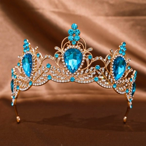 Close-up of golden baroque tiara with blue crystals on dark brown silk background
