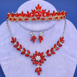 Detalle del conjunto de joyas de novia con cristales rojos y corona floral dorada