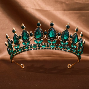 Détail d'une couronne baroque dorée avec gemmes vert émeraude sur soie marron luxueuse