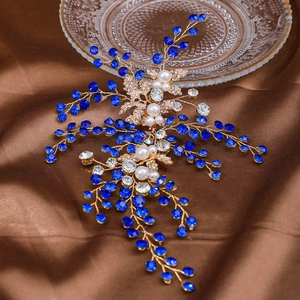 Détails d'un accessoire de coiffure de mariée avec feuilles dorées et cristaux bleus