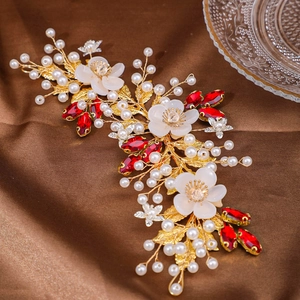 Detail view of bridal hair accessory with white resin flowers and red crystals