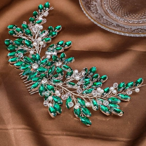 Détail d'un peigne de mariée avec cristaux émeraude et perles sur tissu de satin brun