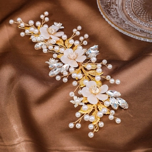 Detail of bridal hair vine with white flowers, pearls and crystals on brown satin