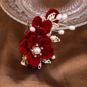 Détail de la pince à cheveux camélia en velours rouge avec feuilles d'or et perles