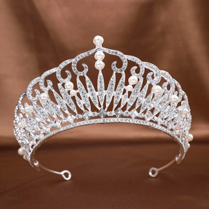 Silver bridal tiara with sparkling rhinestones and white pearls on brown velvet background