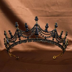 Detailed view of vintage gold crown with black rhinestones on dark silk background