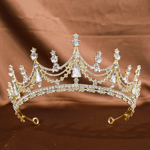 Elegant gold bridal tiara with sparkling crystal rhinestones on a dark silk background