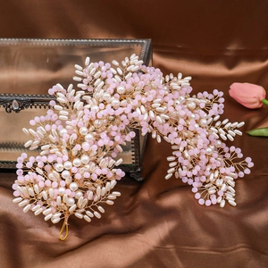 Macro shot of handmade wedding headband with pink beads and white pearls on gold wire