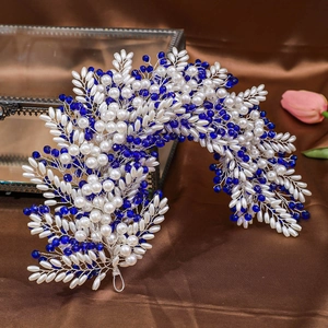 Detail of handmade bridal headband with blue crystals and white pearls on silk background
