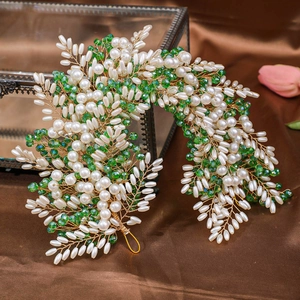 Macro shot of handcrafted bridal headband with emerald crystals and white pearls on satin