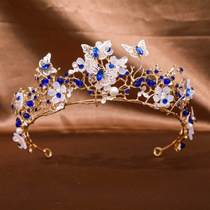 Close-up of golden bridal tiara with blue crystals, white petals and round pearls