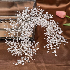 Detailed close-up of handmade bridal headband with pearls and crystals on silk background