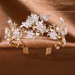 Detailed shot of golden bridal tiara with green rhinestones, pink flowers and white pearls