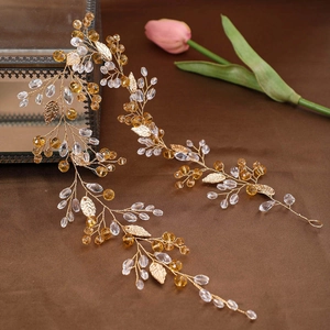 Detailed macro view of handmade golden bridal hair vine with crystal beads and metal leaves