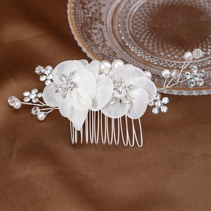Détail de fleurs en soie blanche et branches d'étoiles en cristal sur peigne de mariée