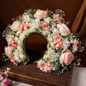 Dettaglio della corona di fiori rosa e bianchi fatta a mano su un vassoio di legno