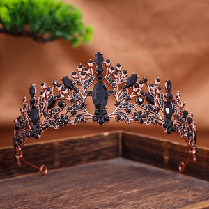 Detailed view of vintage rose gold crown with inlaid black crystals on wooden tray