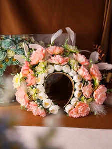 Dettaglio di fiori di seta rosa con perle e piume su una fascia floreale per capelli