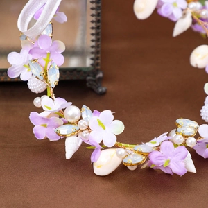 Detail of handmade bridal headband featuring purple fabric flowers, shells and white pearls