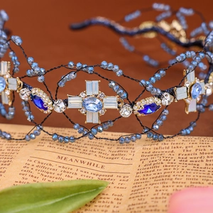 Macro detail of handmade mesh headband with blue crystals and vintage cross star ornament