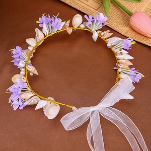 Detail of seashell headband with purple flowers, pearls, and a white organza bow tie